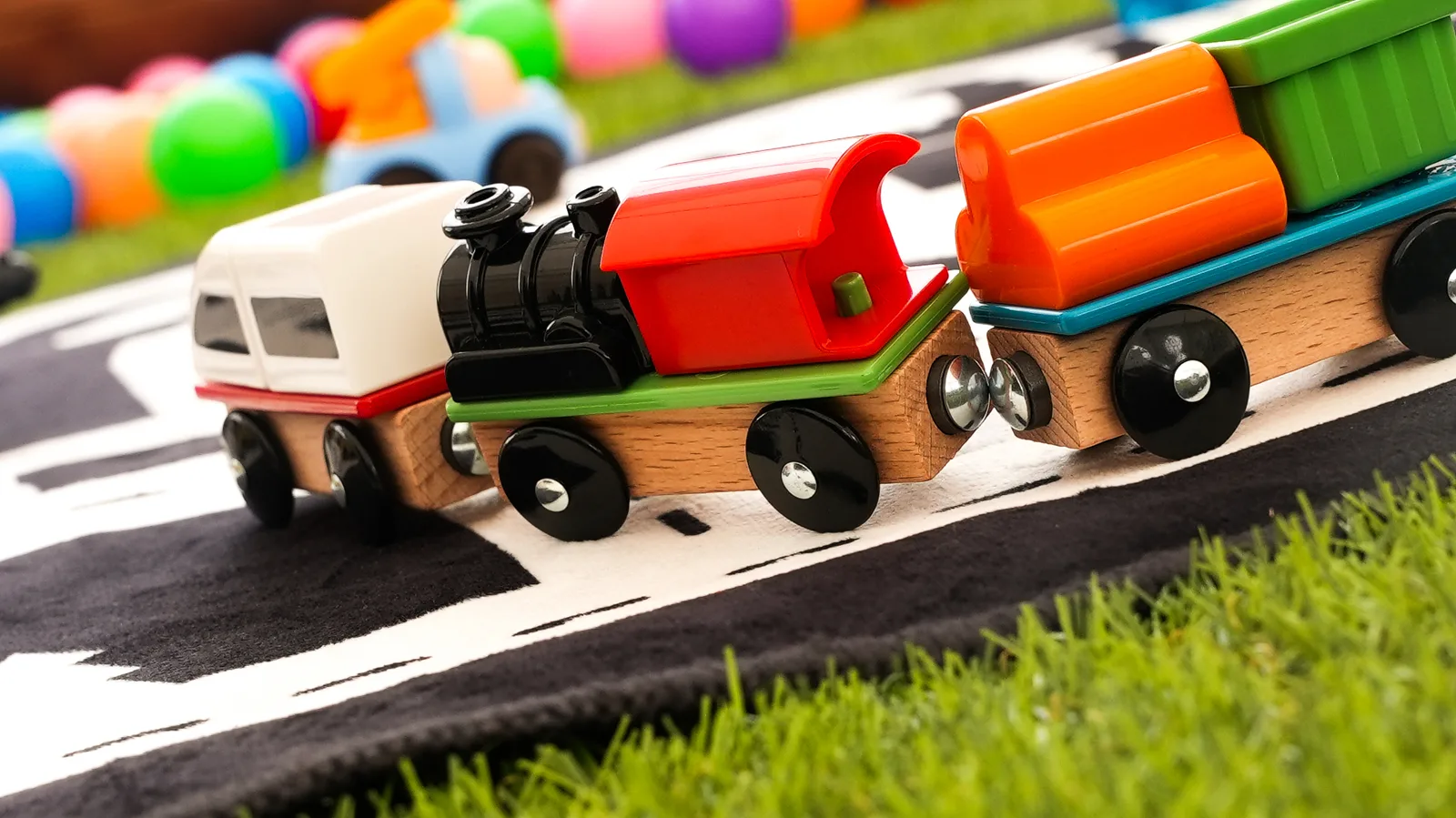 Train en bois avec wagons colorés sur tapis circuit pour atelier enfant