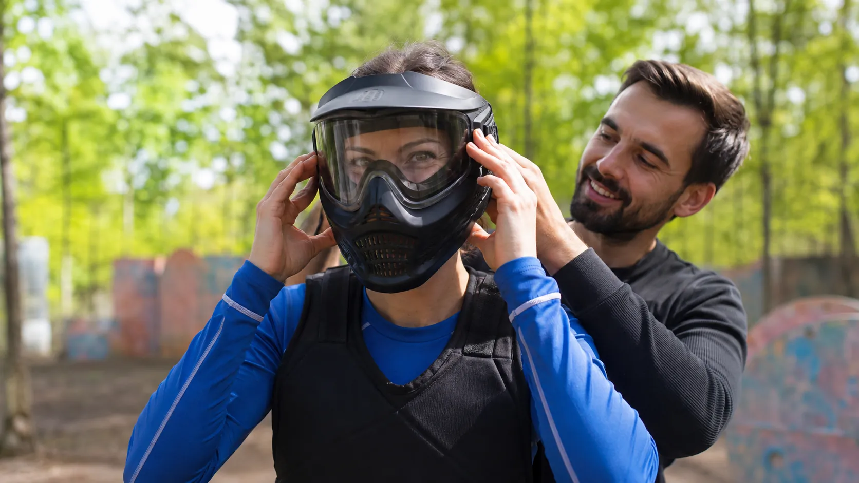 Une joueuse ajuste un véritable masque de paintball avec l’aide d’un animateur