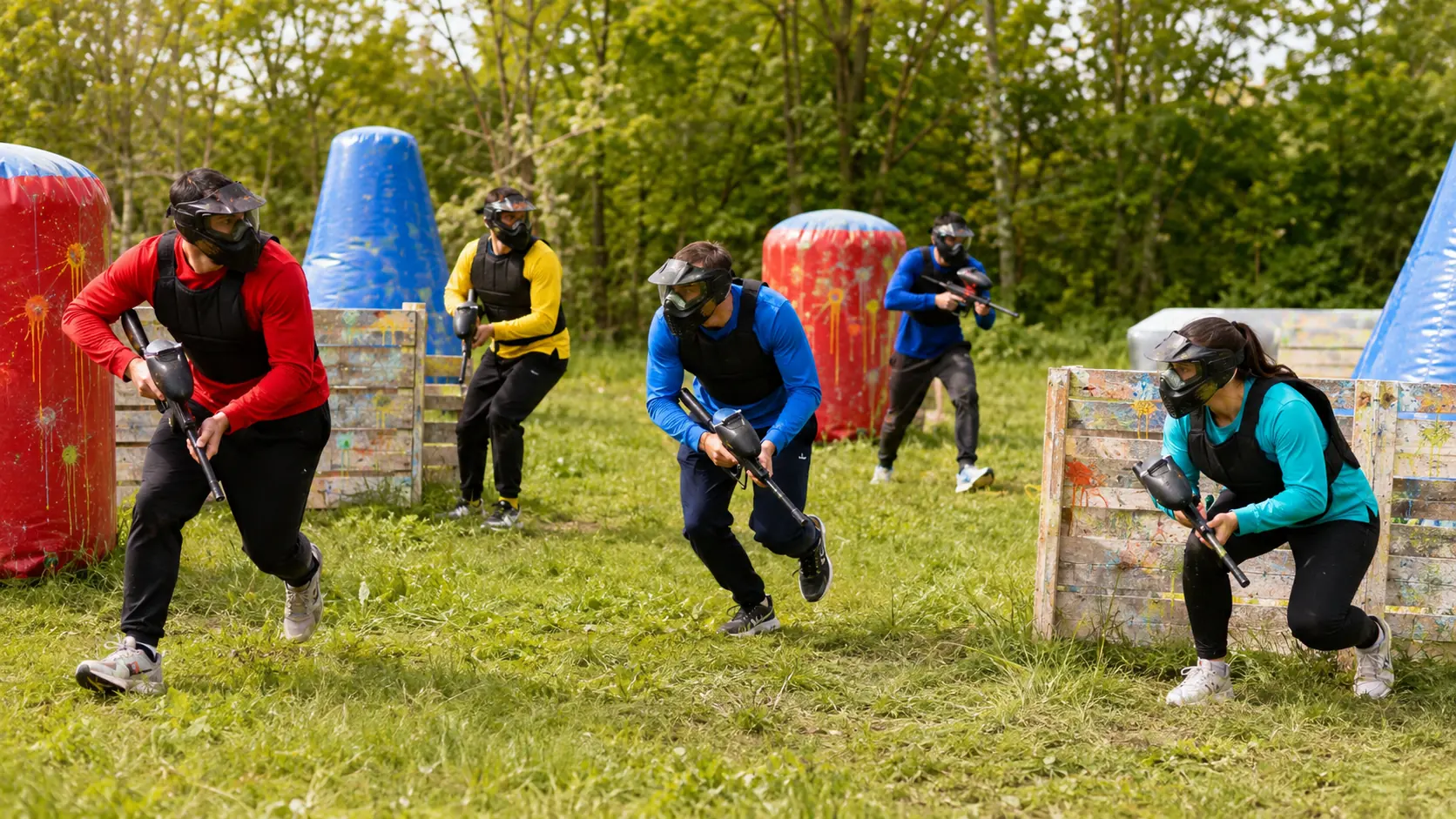 Cinq joueurs progressent entre des obstacles colorés sur un terrain de paintball près de Fontenay-sous-Bois