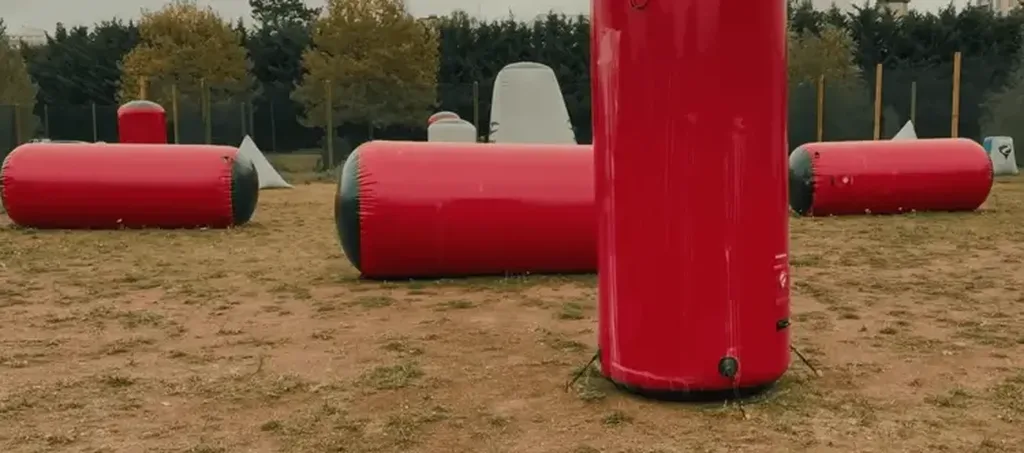 Obstacles gonflables rouges et blancs installés sur un terrain de jeu en terre battue
