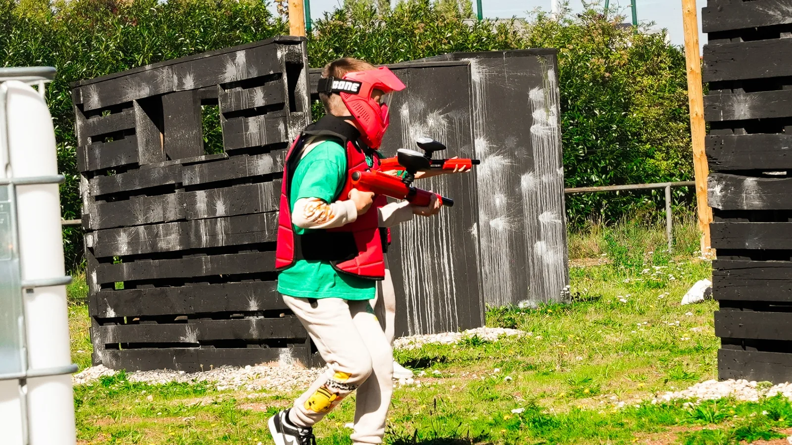 Enfant en pleine action sur terrain paintball outdoor scénarisé