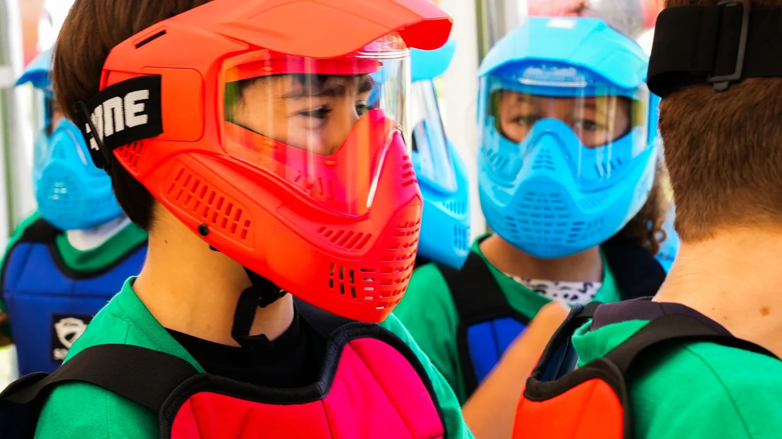 Enfants équipés de masques intégraux colorés et plastrons de protection paintball