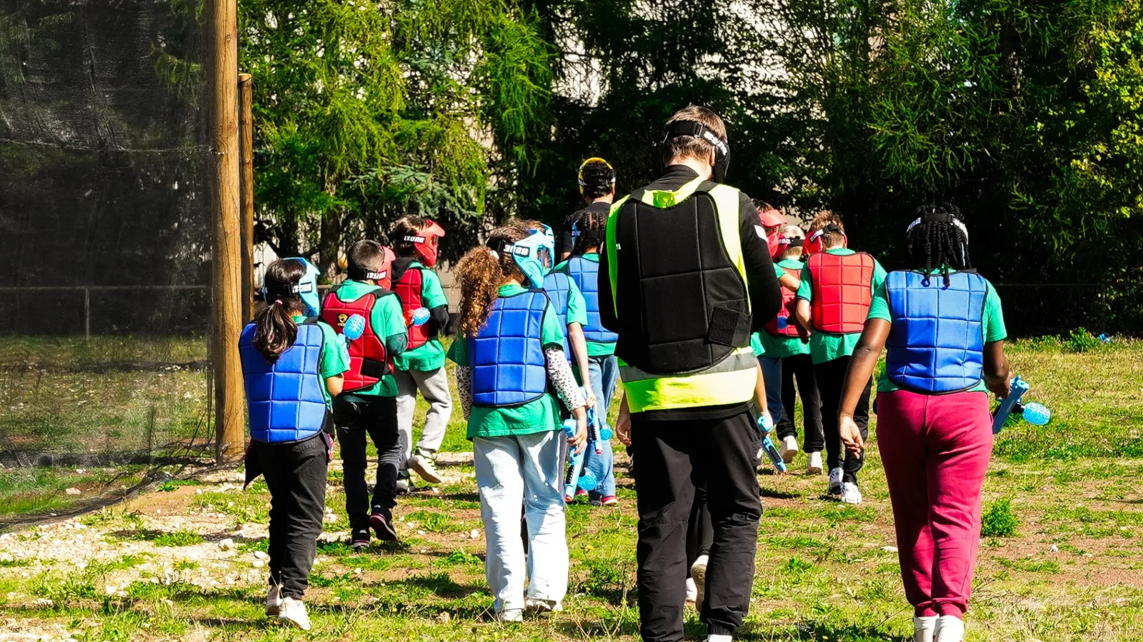 Groupe d'enfants équipés de plastrons et lanceurs Gel Blaster bleus encadrés par un moniteur