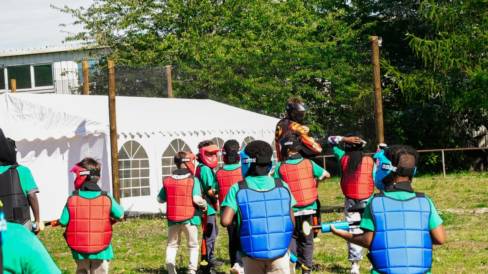 Groupe d'enfants équipés de plastrons rouges et bleus en sortie paintball