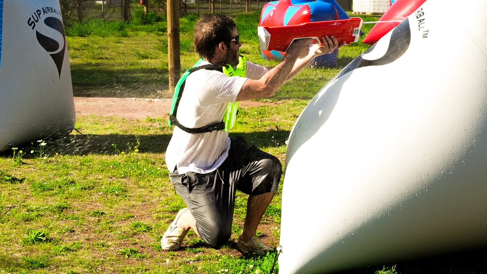 Joueur Water Battle genou à terre en position de tir avec lanceur rouge