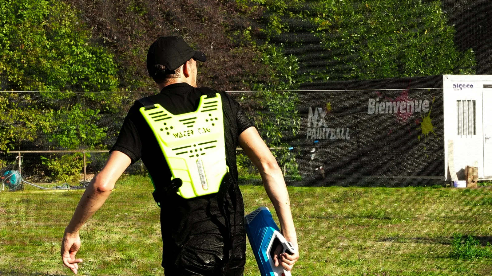 Plastron Water Tag NX Paintball et lanceur bleu devant les filets du terrain