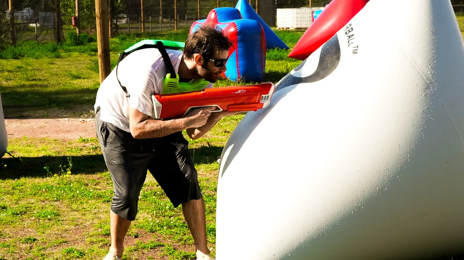 Joueur Water Battle en visée avec lanceur rouge derrière obstacle airball
